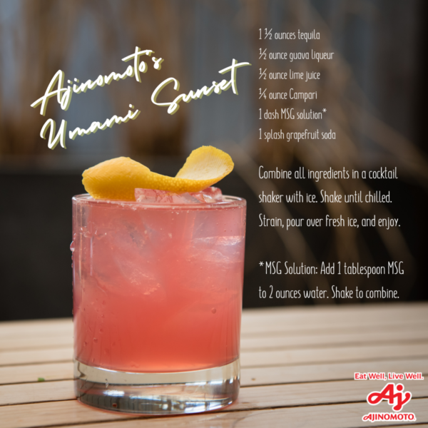 A pink cocktail garnished with a lemon twist sits on a wooden surface, with a recipe for Ajinomoto’s Umami Sunset displayed beside it.